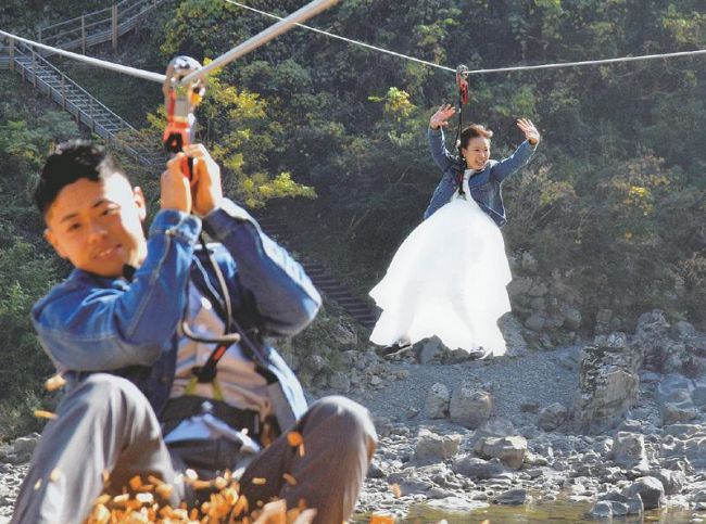 四万十川ジップラインを滑空する結婚式を挙げた石本天真さん＝手前、久代さん夫妻（四万十町十和川口）
