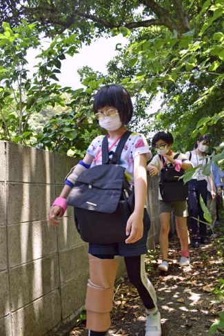 動きを制限する器具を着けて避難路を歩く浦戸小児童（高知市浦戸）