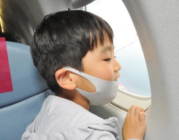 飛行機の窓にかぶり付いて景色を楽しむ子ども