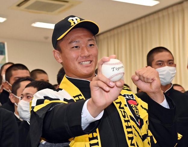 プロ野球ドラフト会議で阪神に１位指名された高知高の森木大智投手。球団の帽子と法被姿でポーズを決めた　（高知市旭天神町）