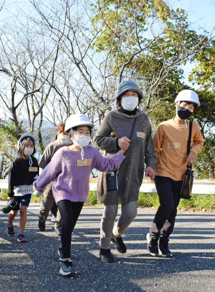 避難訓練で手をつないで歩く児童と地域住民（高知市浦戸）