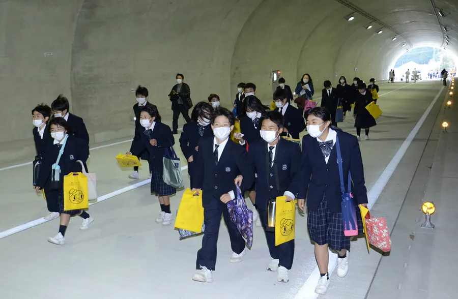 開通前の野越バイパスでトンネル内を歩く児童ら（津野町北川）