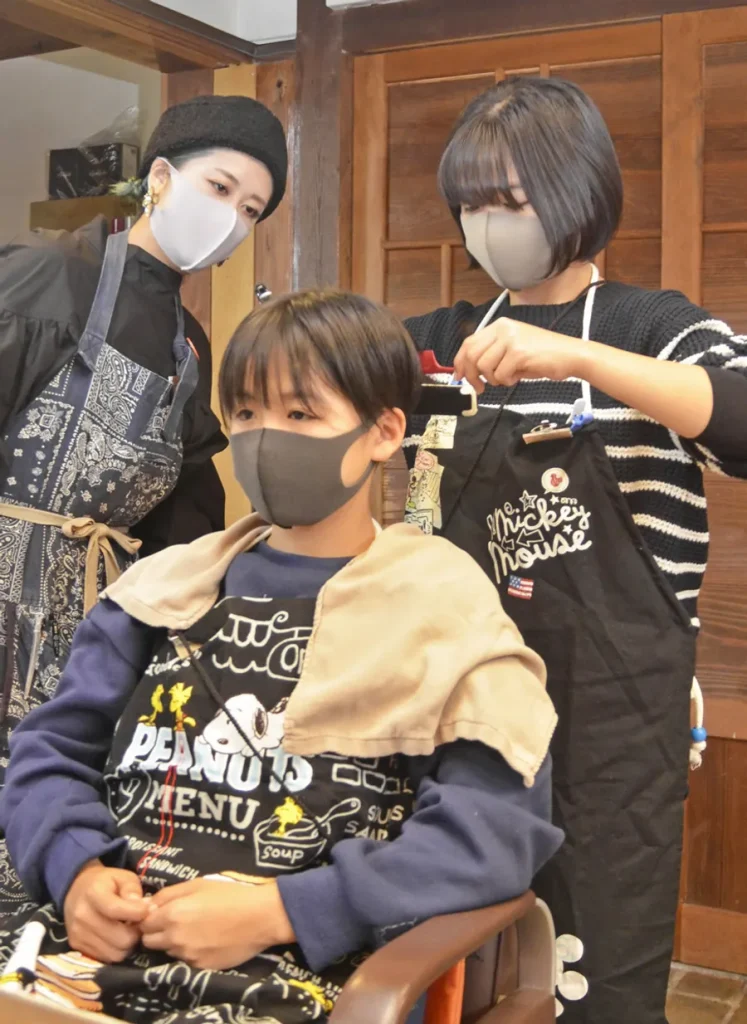 美容師体験でヘアアイロンを扱う中学生（高知市伊勢崎町の「テントヘアー」）