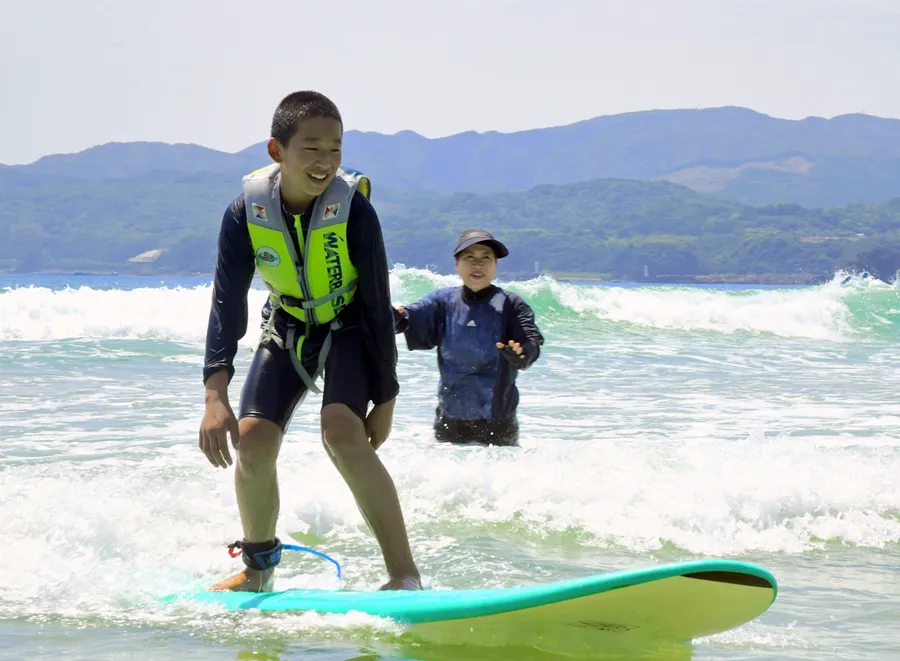 白い波をつかまえてサーフィンを楽しむ幡陽小学校の児童（土佐清水市大岐）