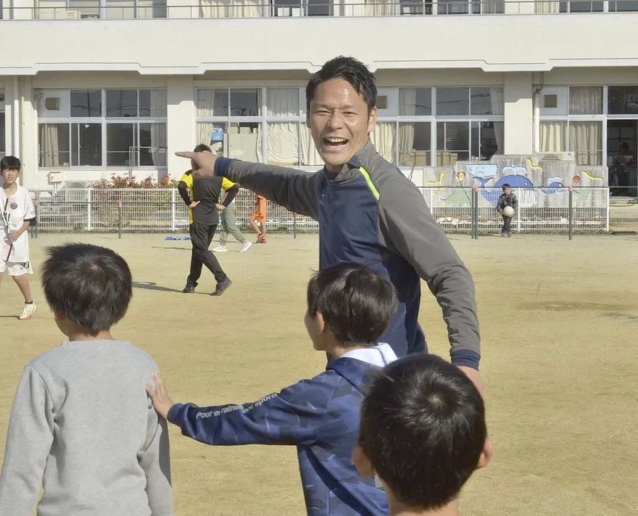 児童とサッカーを楽しむ中村元樹さん　（南国市の久礼田小）