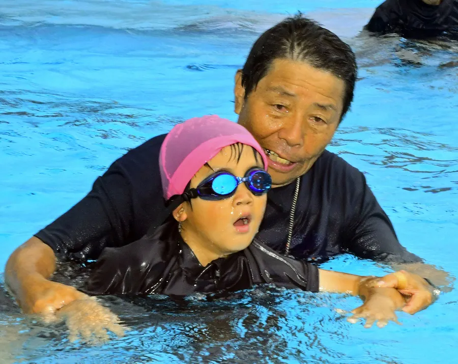 教室の開設時から児童に泳ぎ方を教える岩井さん（右）