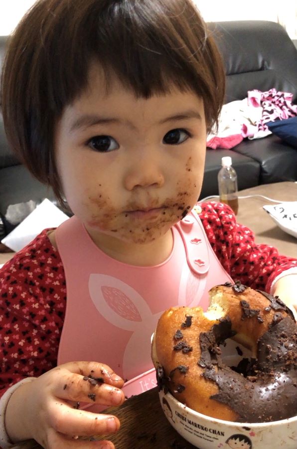 顔じゅうにチョコをつけながら一生懸命ドーナツを食べる小さい頃の写真です