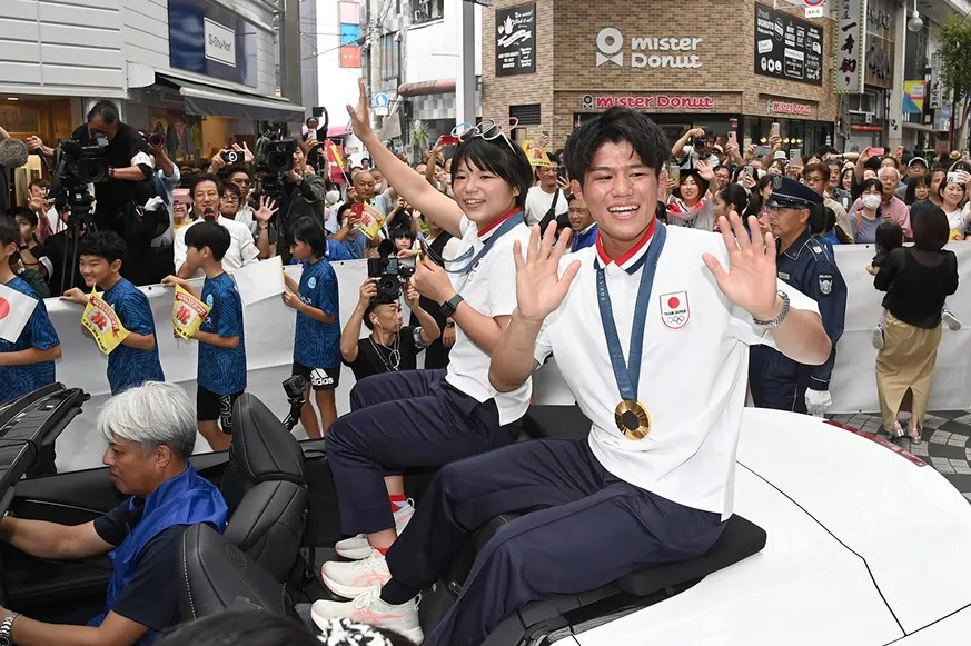 大勢の県民の祝福に、笑顔で手を振る清岡幸大郎選手＝右＝と桜井つぐみ選手（高知新聞2024年9月30日掲載）