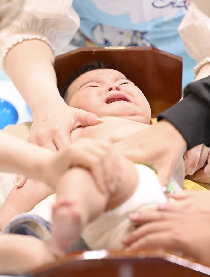 大泣きの赤ちゃんも、固定するスタッフの皆さんも必死!